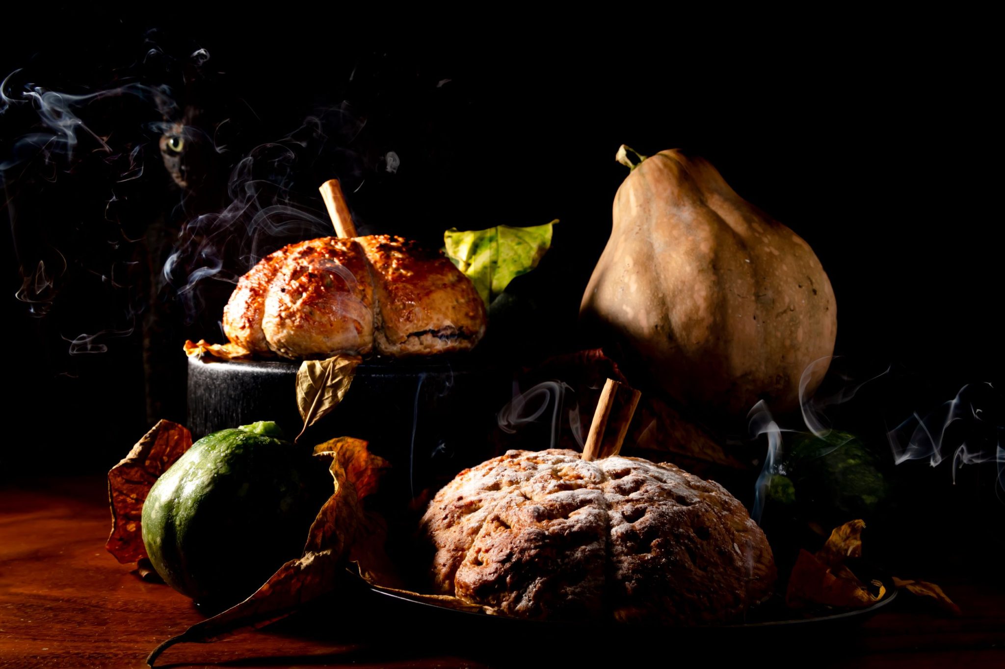 moody shot of pumpkin shaped bread with gourds
